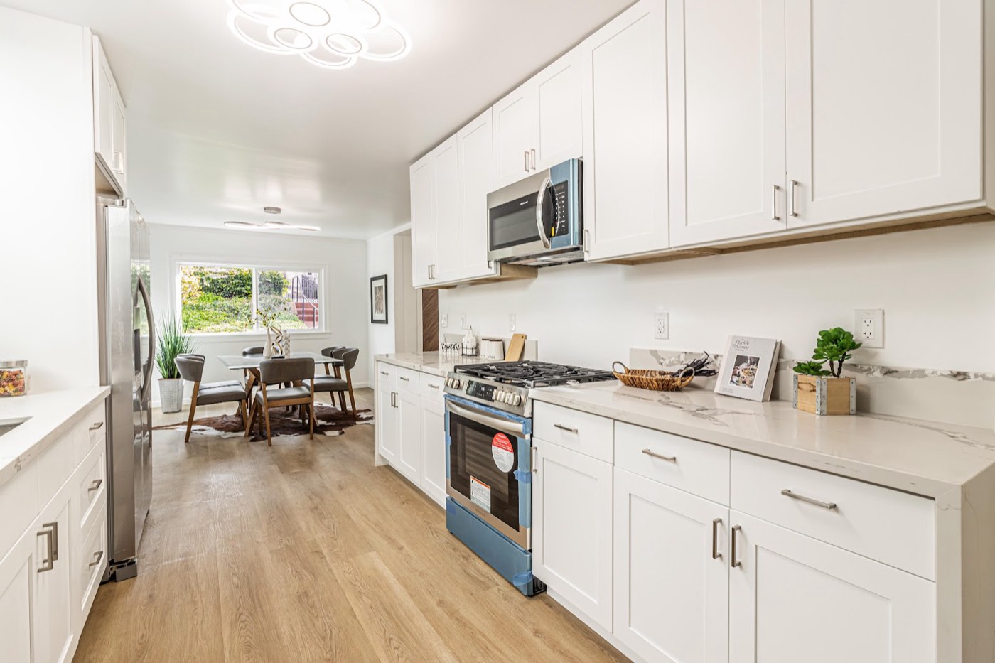 Remodeled white galley kitchen with marble counters