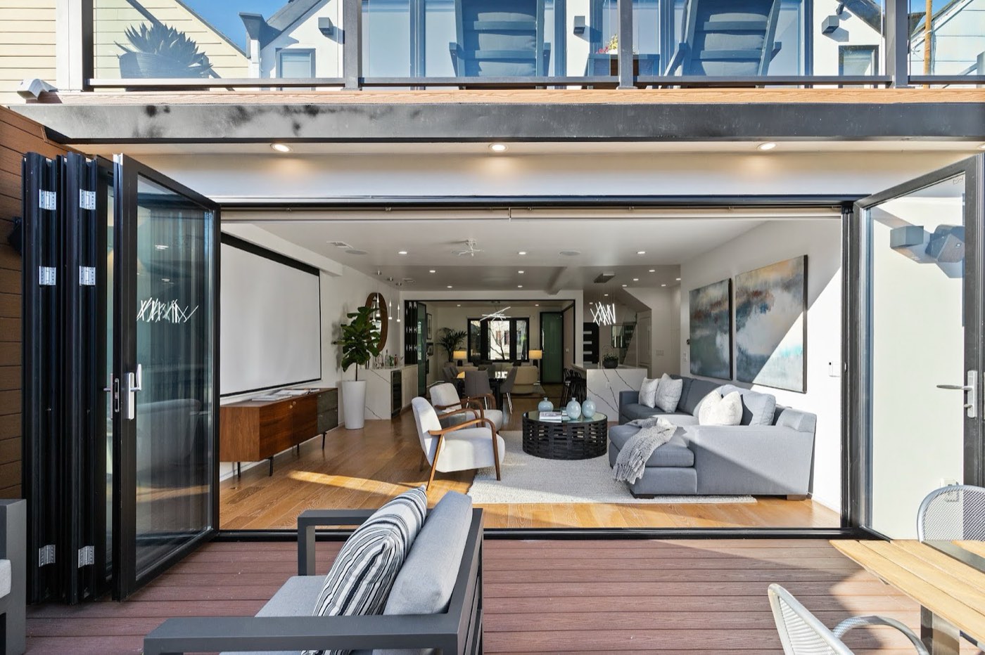 Modern living room opening to a terraced backyard through folding glass walls