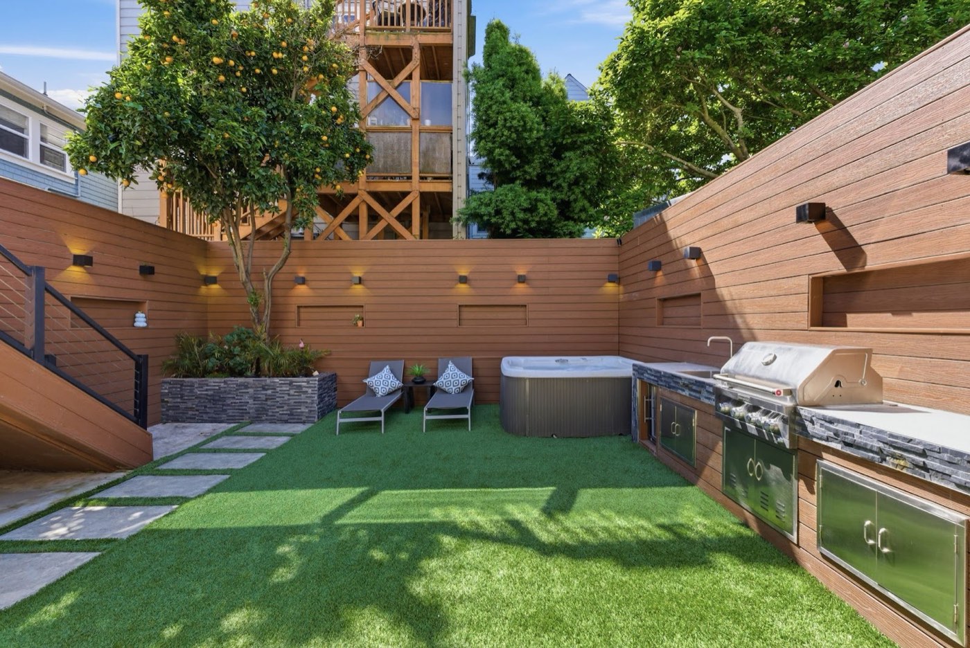 Backyard with outdoor kitchen, hot tub, and turf lawn